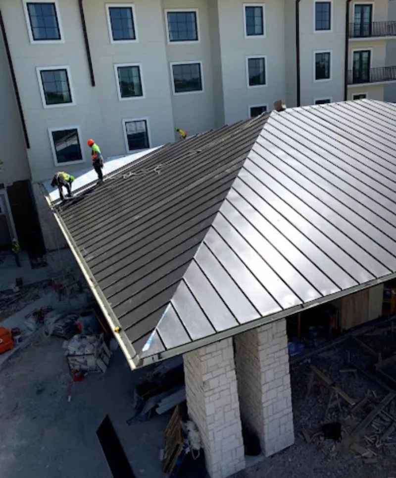 Crew installing standing seam metal roof panels on a commercial project in Godfrey